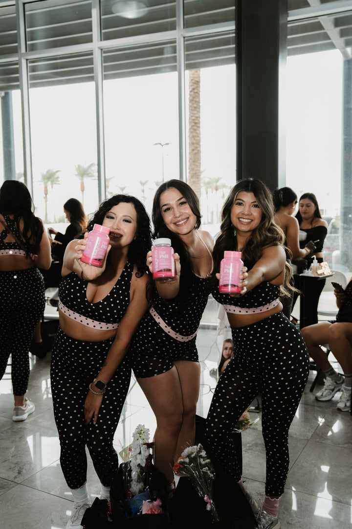 Women holding Vita Globe Her PMS gummies at a SimplicityCo Movement Pilates event