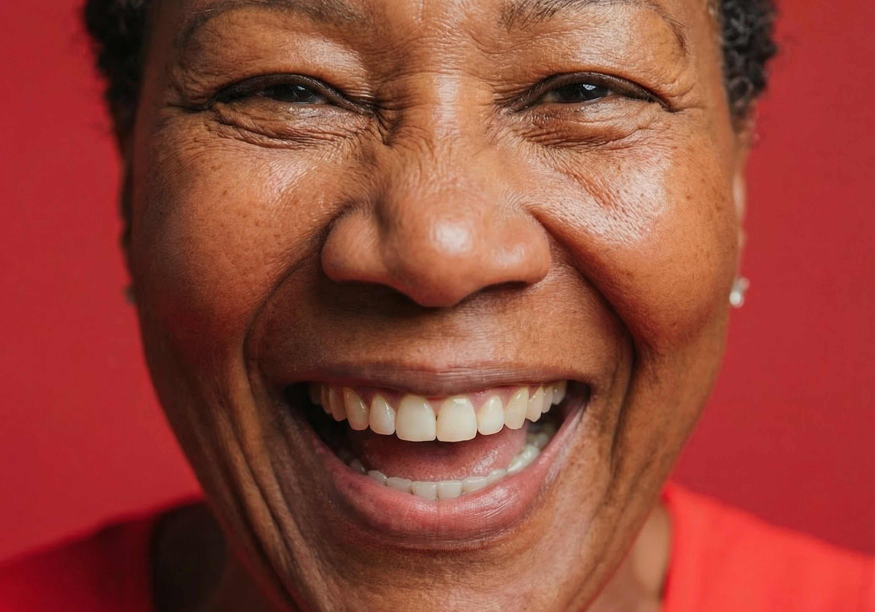 Close-up portrait of a smiling woman with short gray hair wearing a red top