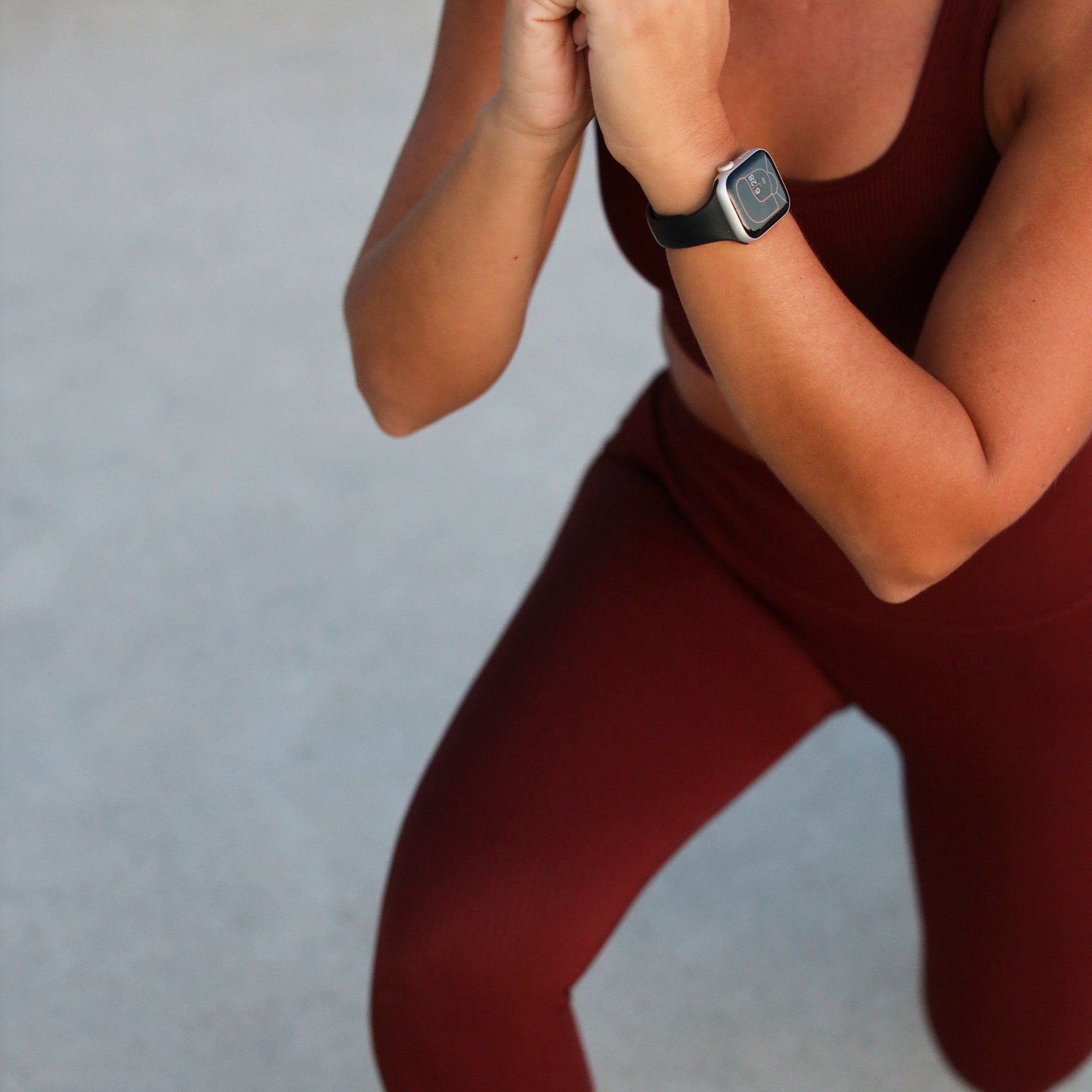 Woman in maroon activewear holding a lunge, wearing a fitness watch