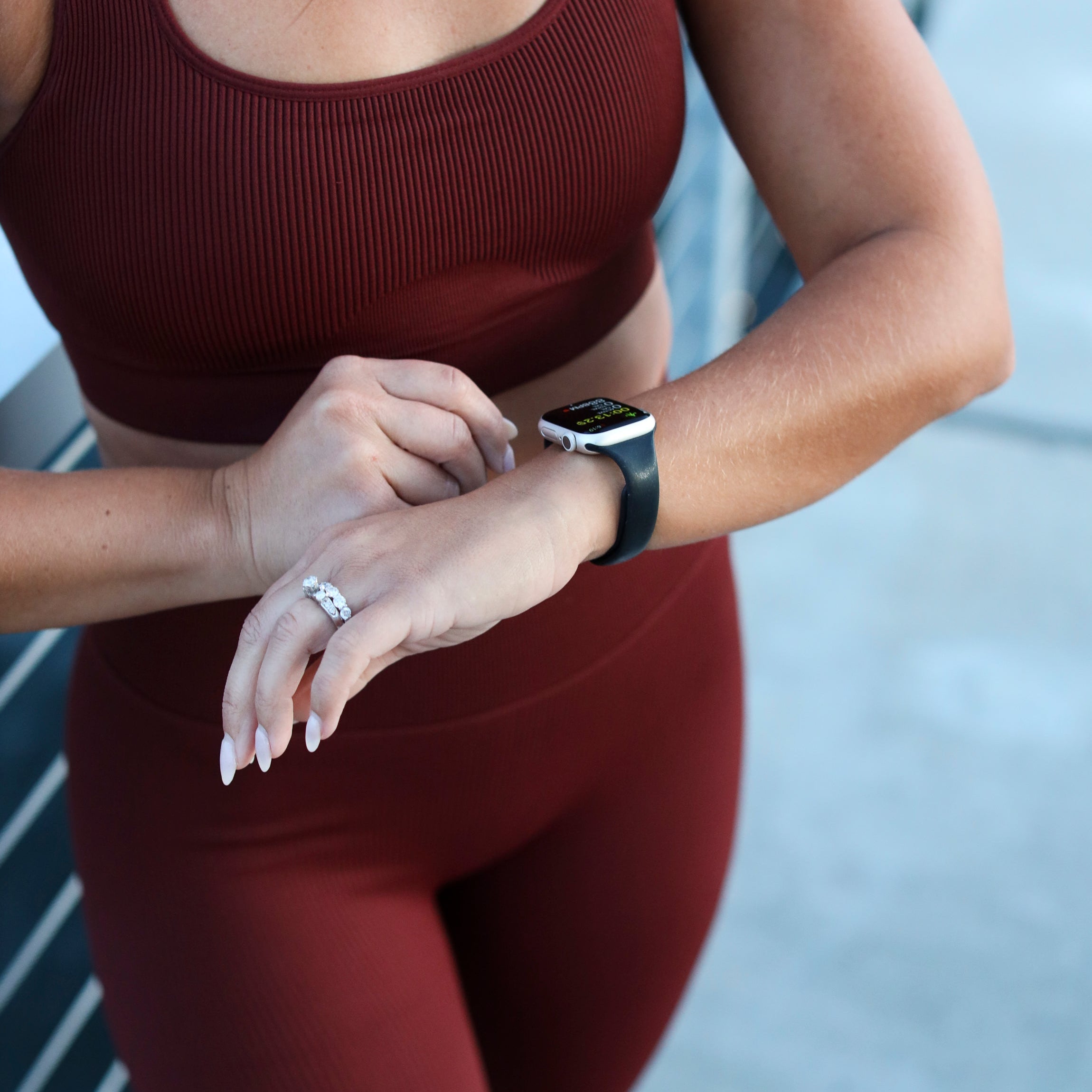 Woman in maroon activewear checking her smartwatch after a workout