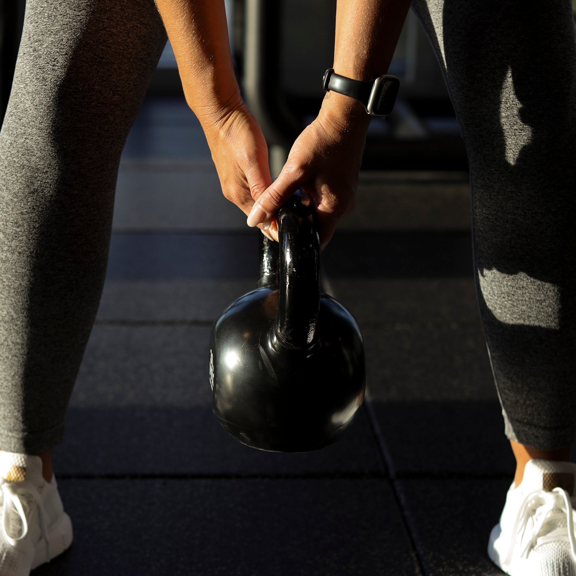 Person lifting a kettlebell off a gym floor