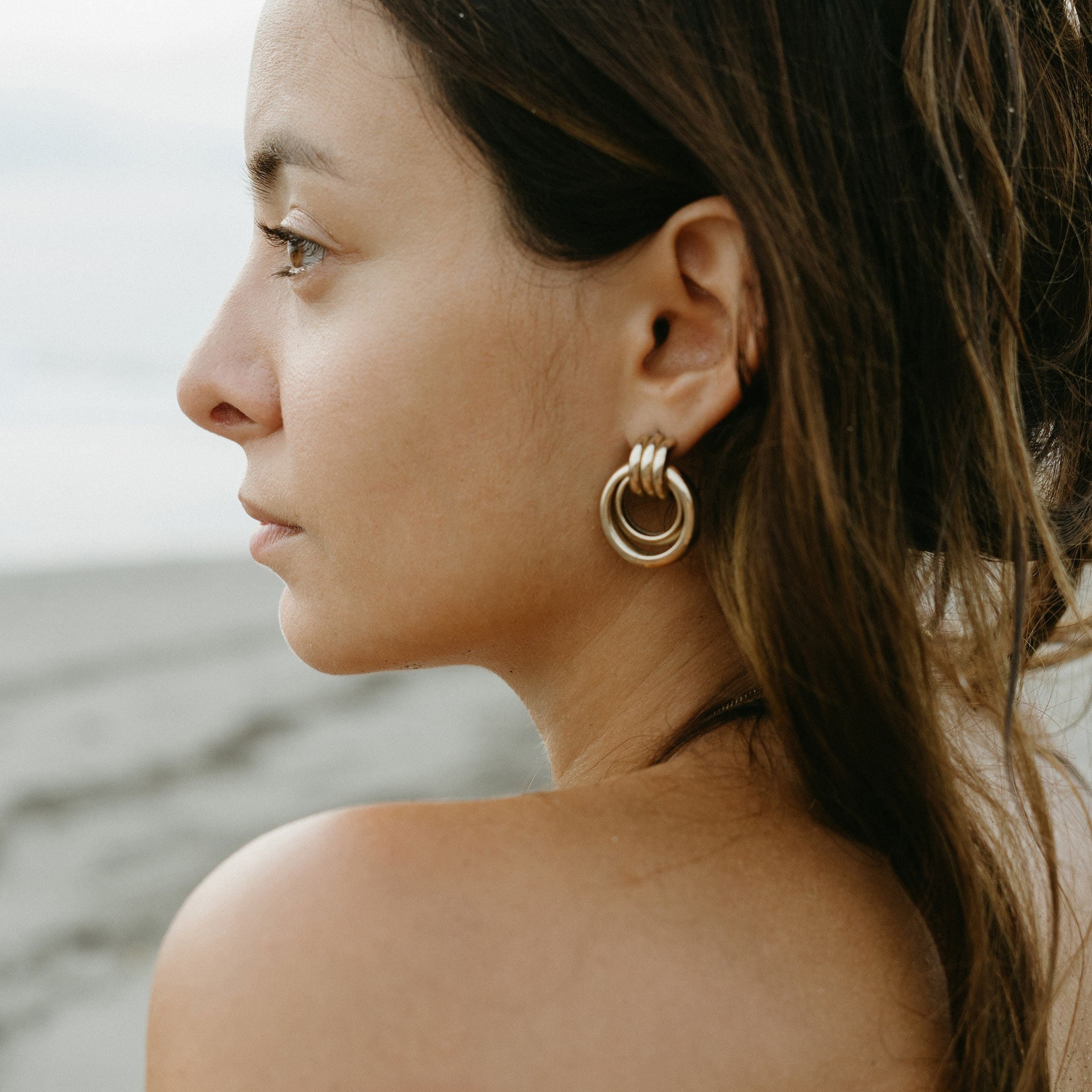 Profile view of a woman with glowing skin and a gold hoop earring