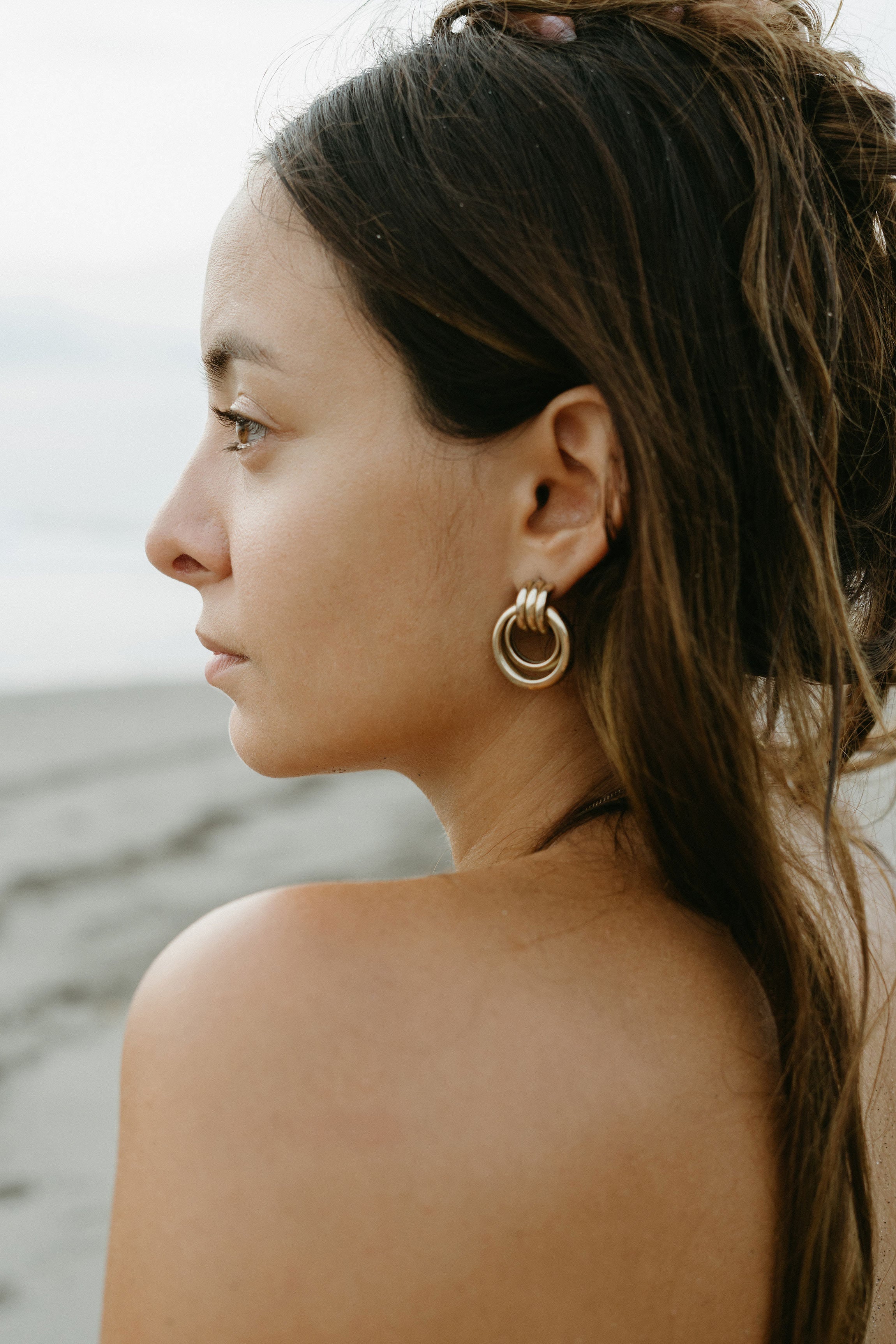 Profile view of a woman with glowing skin and a gold hoop earring