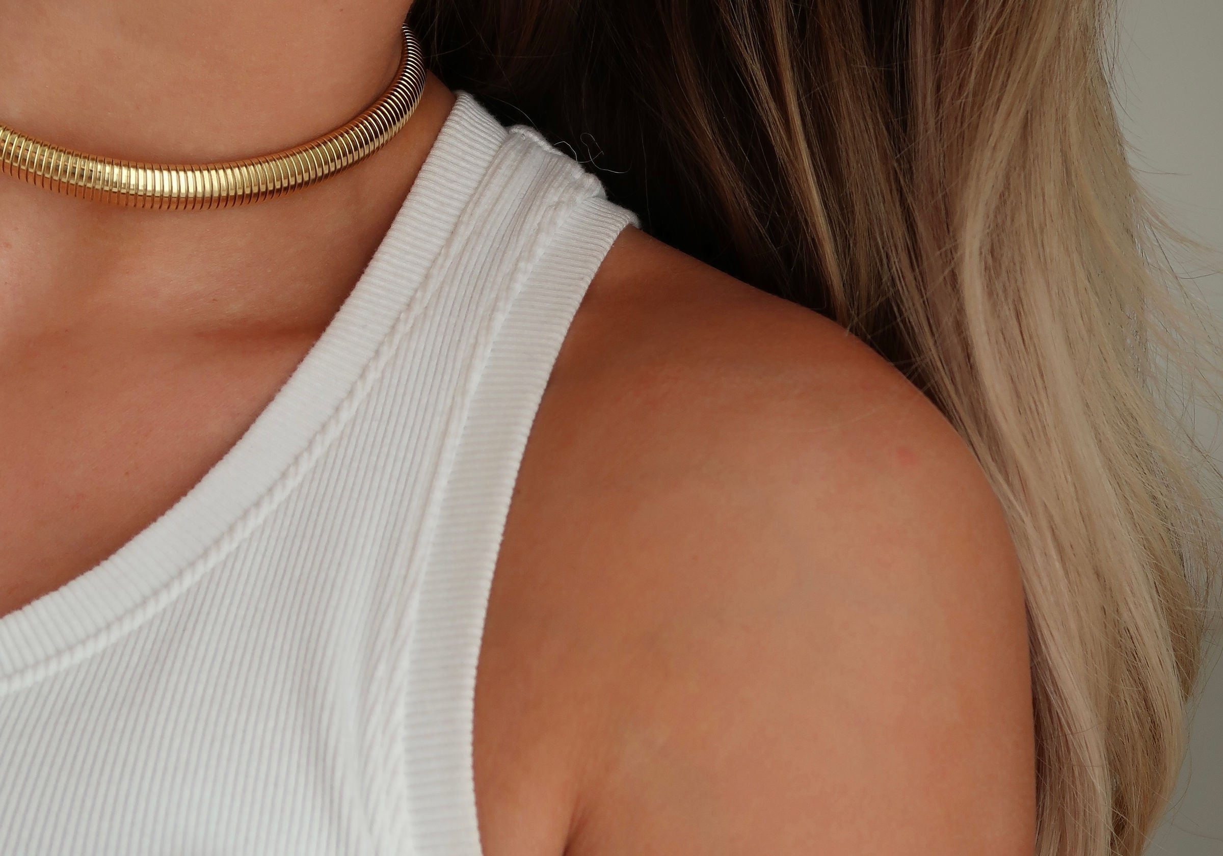Woman with glowing skin and gold jewelry, showcasing healthy hair and radiant skin