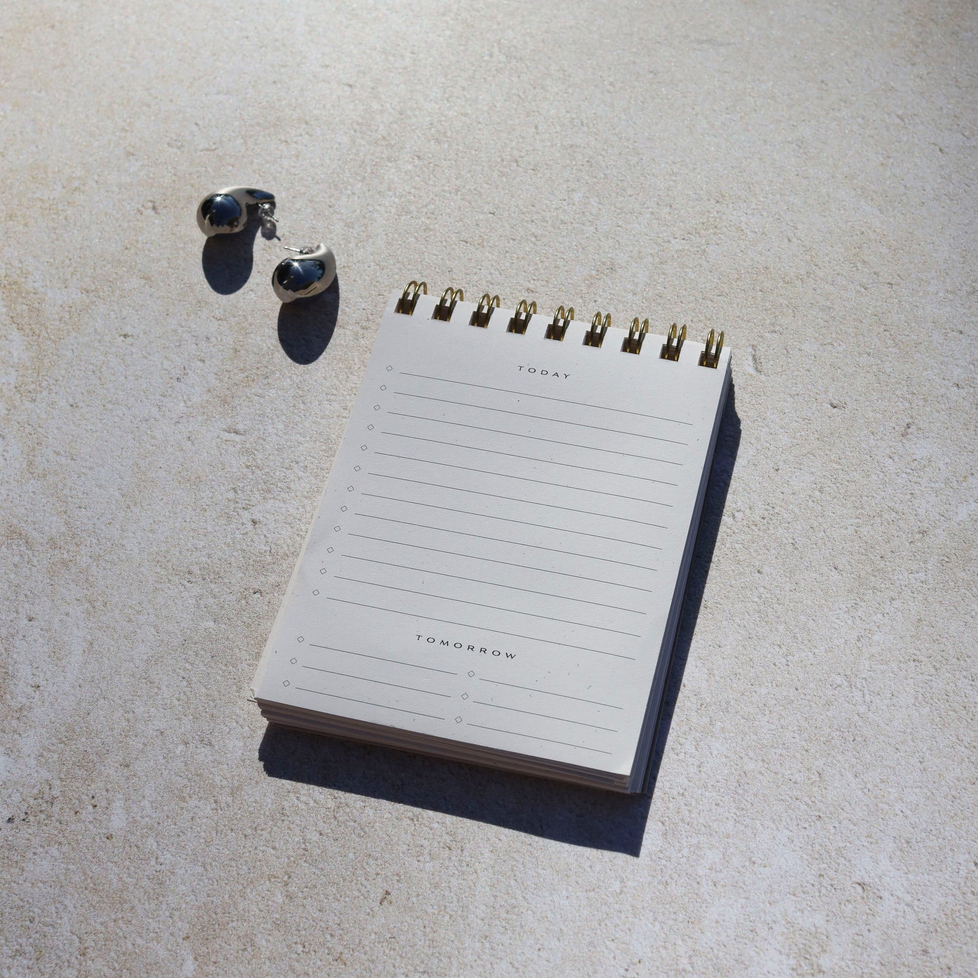 Notepad and wireless earbuds on a concrete surface