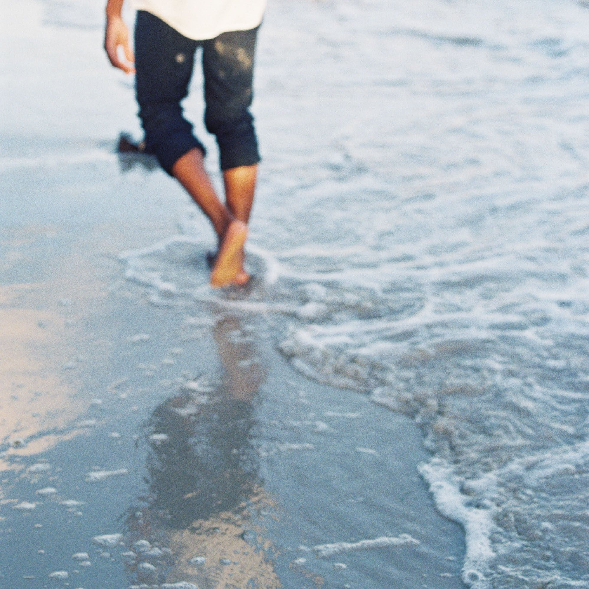 Person walking barefoot along the shoreline