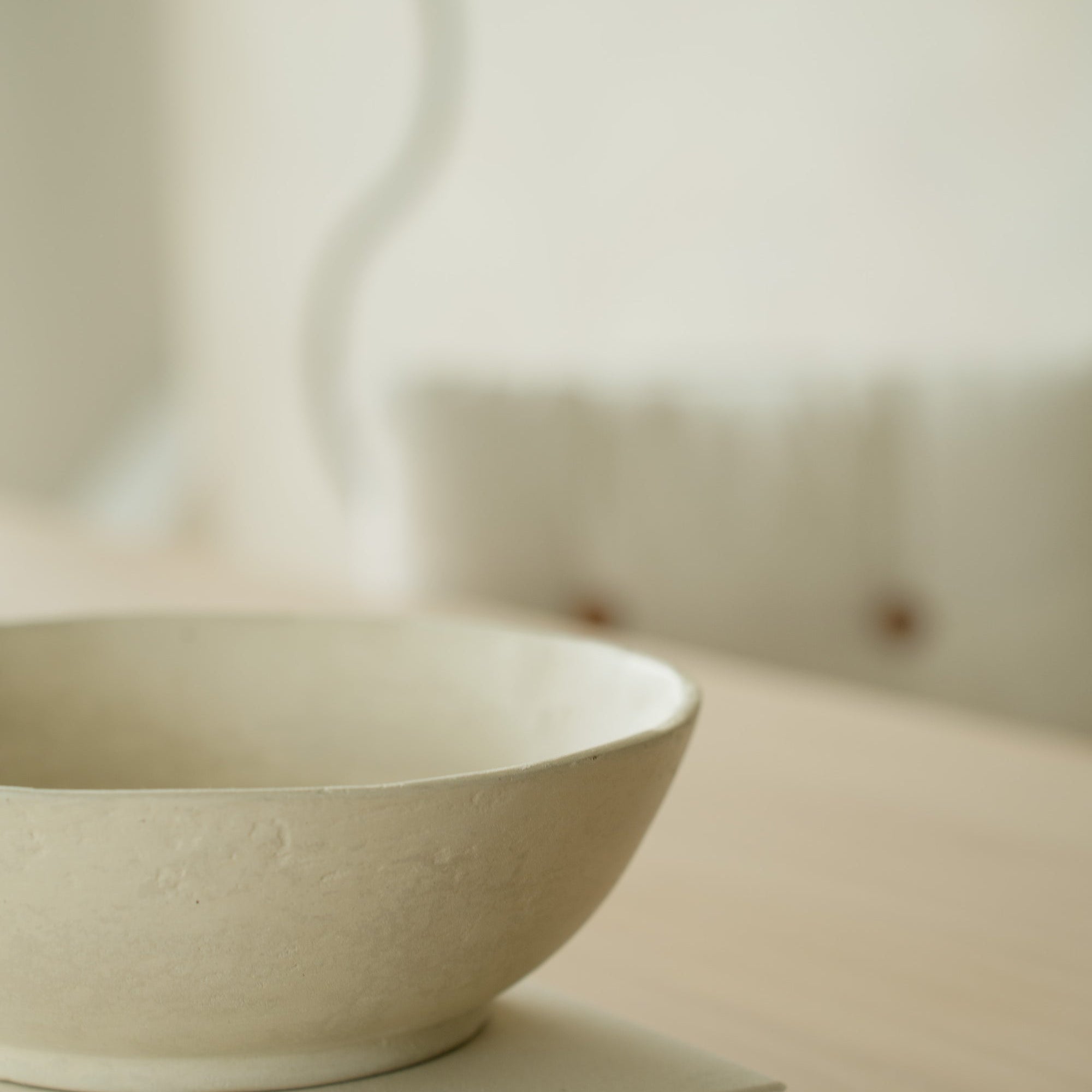 Ceramic bowl resting on a book on a table in warm light