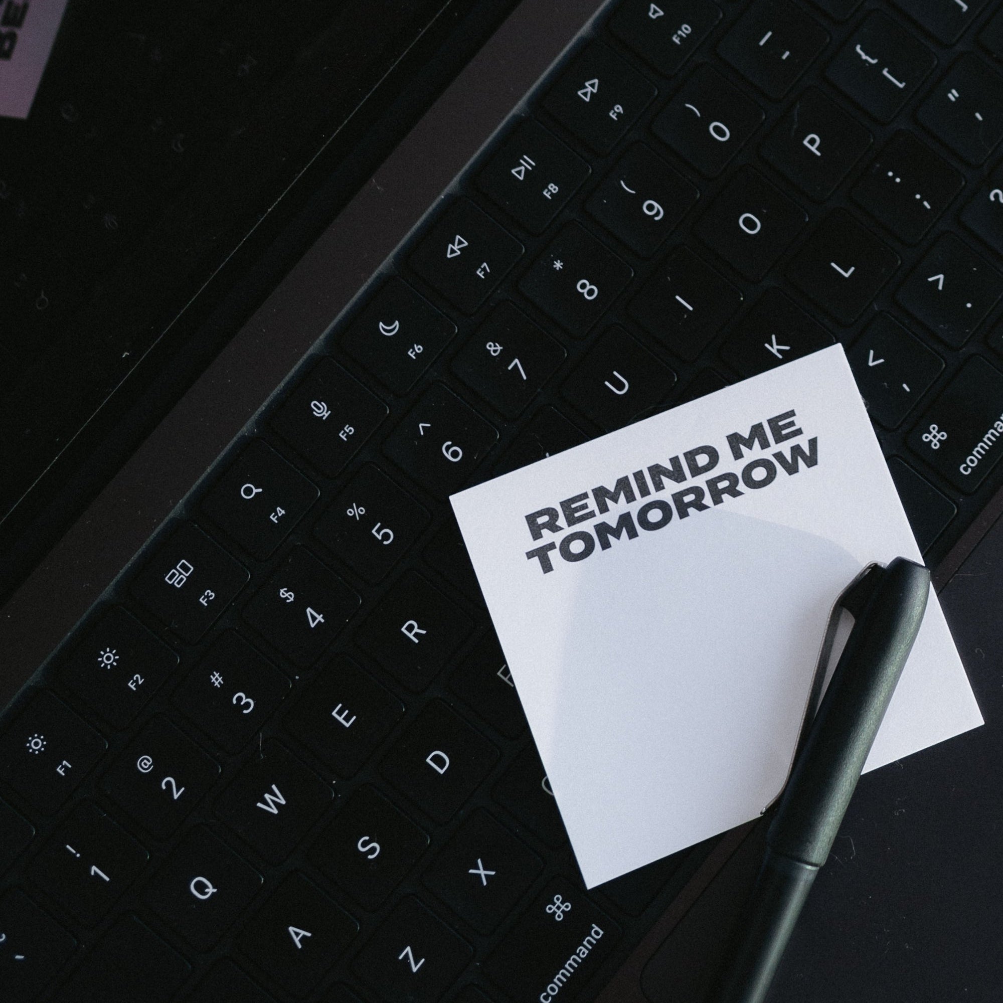 Sticky note reading 'Remind me tomorrow' on a laptop keyboard