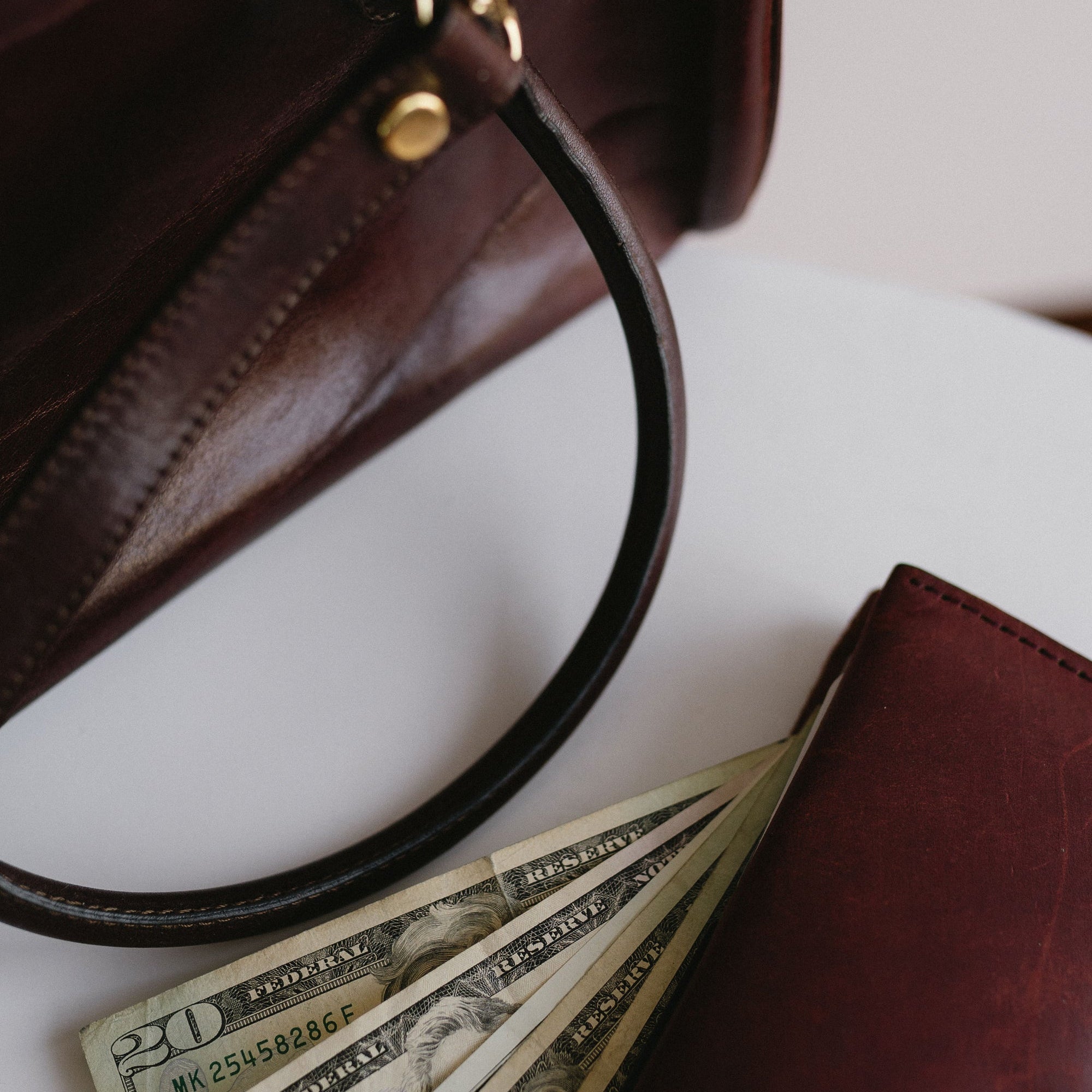 Leather handbag, wallet and cash on a table