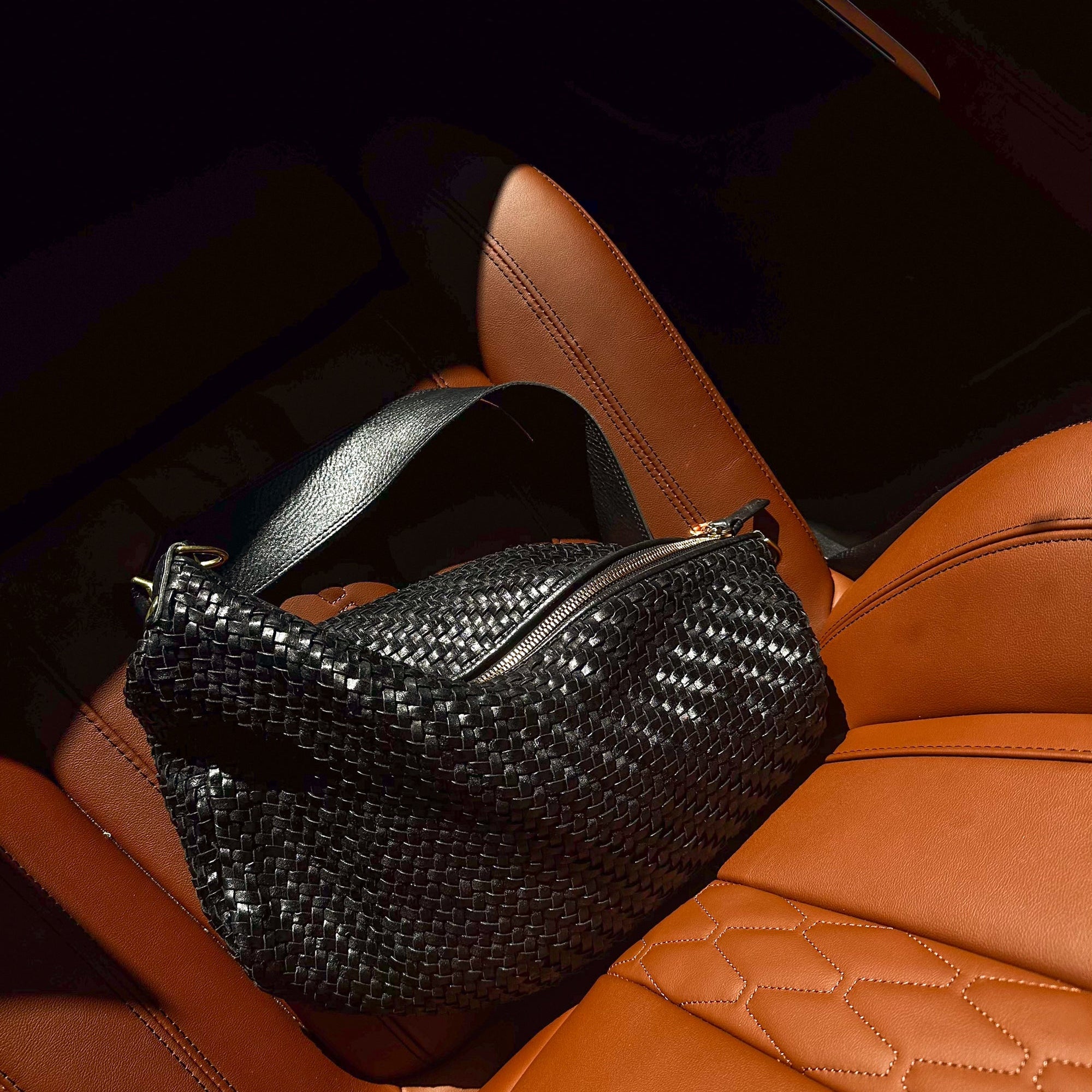 Woven handbag on a tan leather car seat