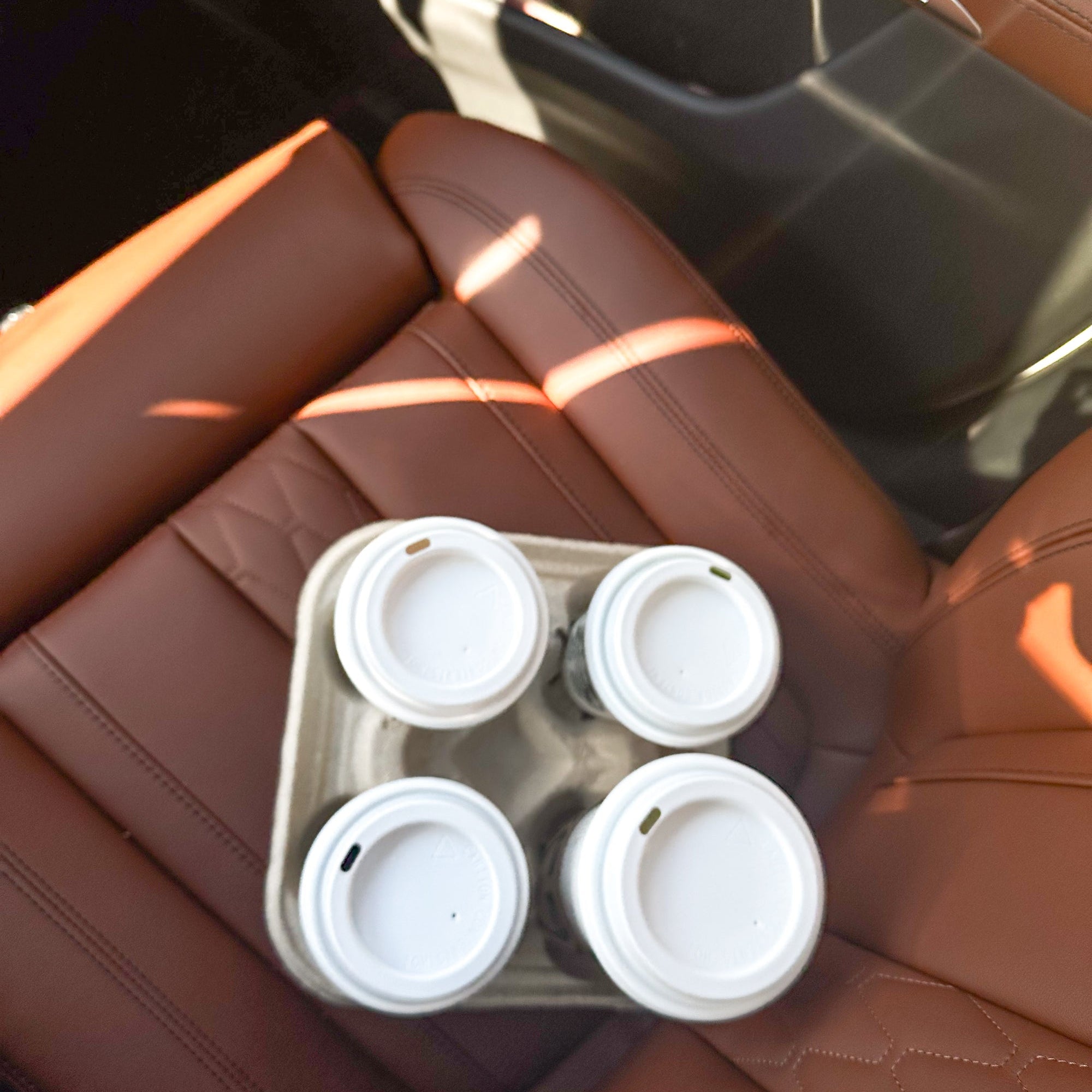 Tray of four takeaway coffee cups on a car seat