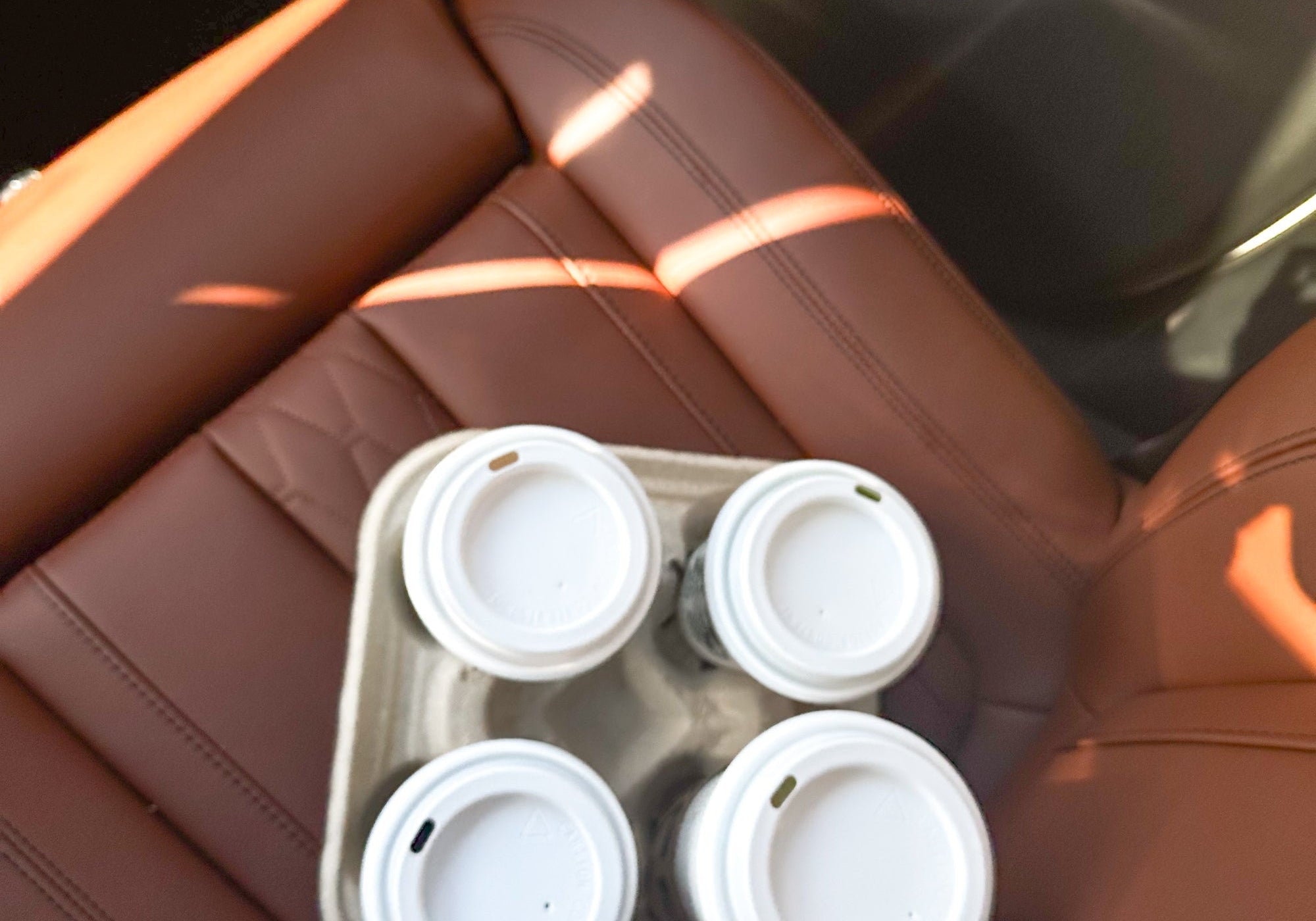 Tray of four takeaway coffee cups on a car seat