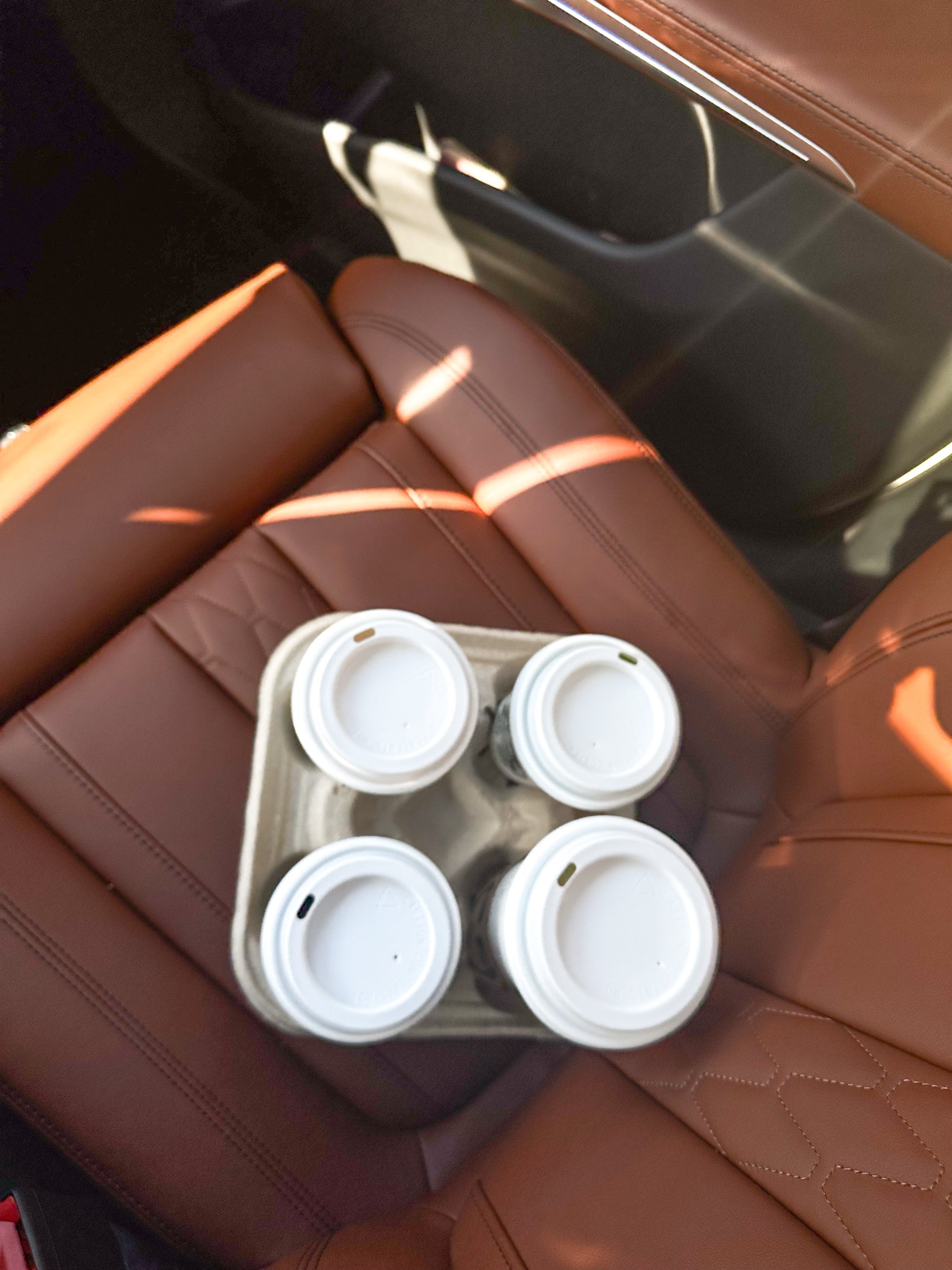 Tray of four takeaway coffee cups on a car seat