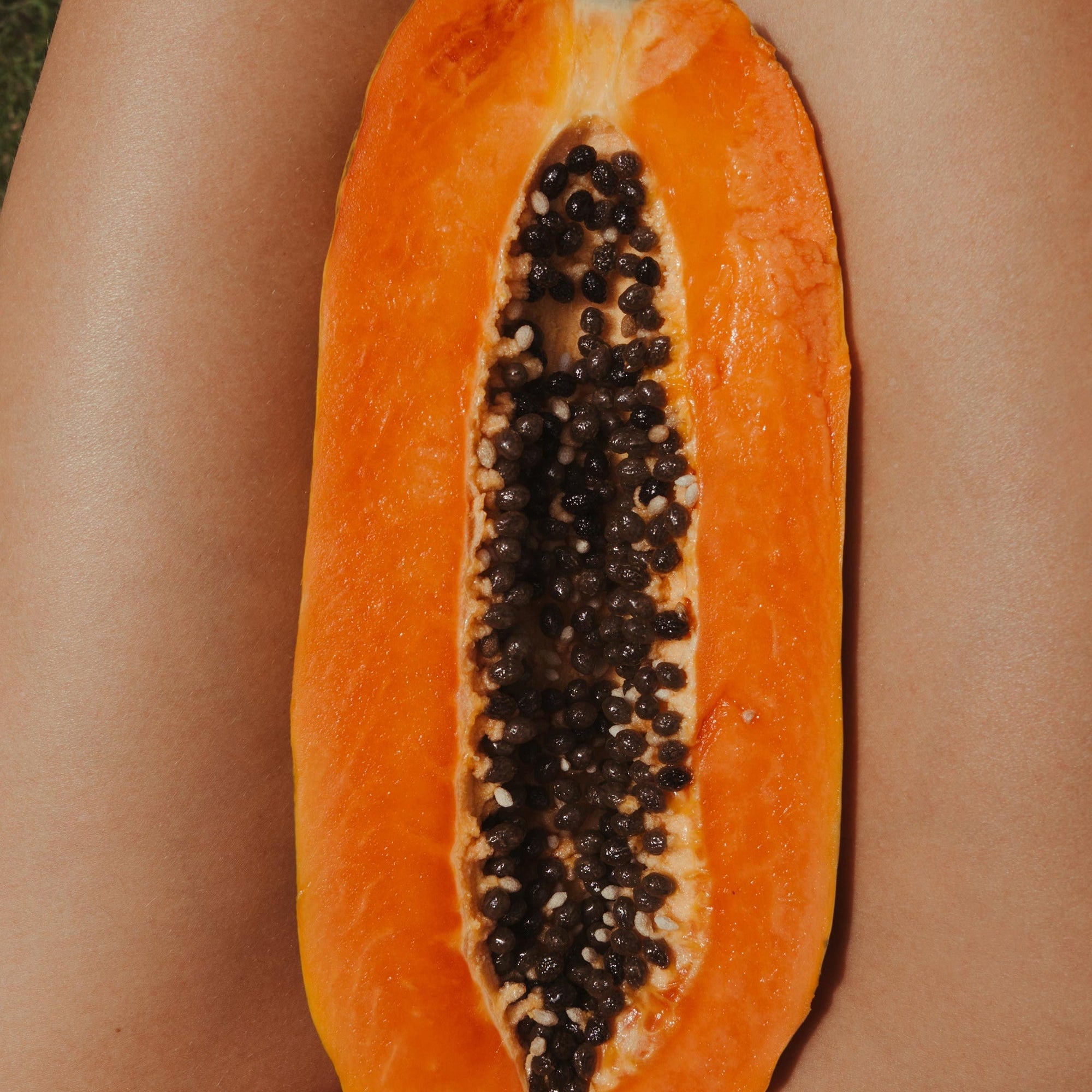 Halved papaya resting on a person's lap