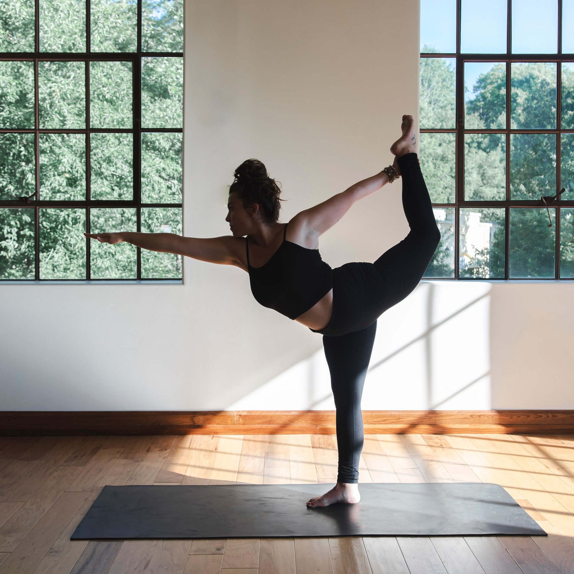 Woman holding a standing yoga balance in a sunlit studio