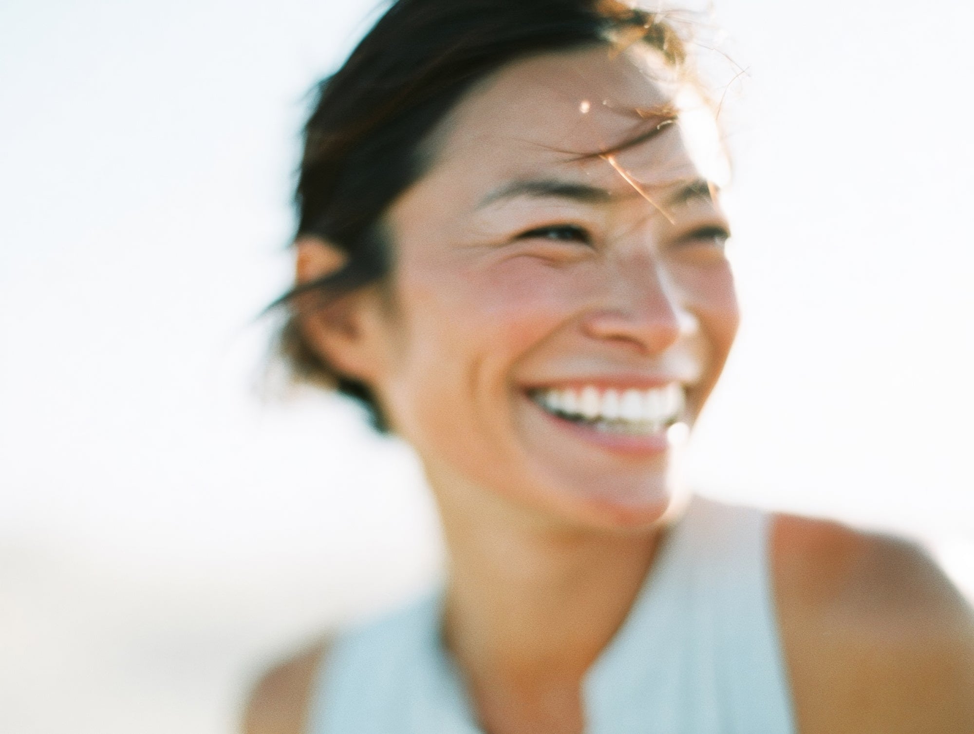 Smiling woman with freckles squinting in bright sunlight