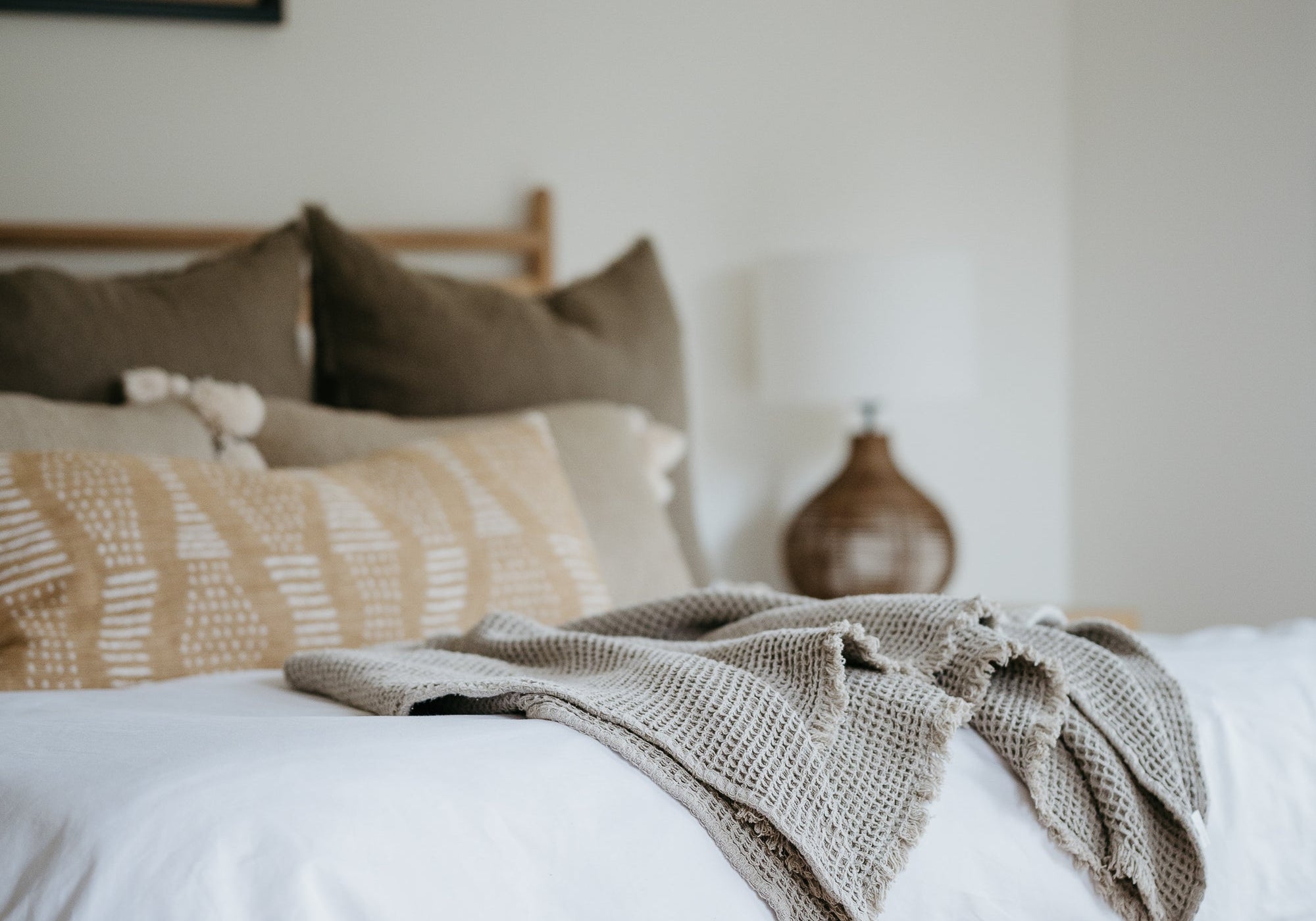 Neatly made bed with white linens and neutral pillows