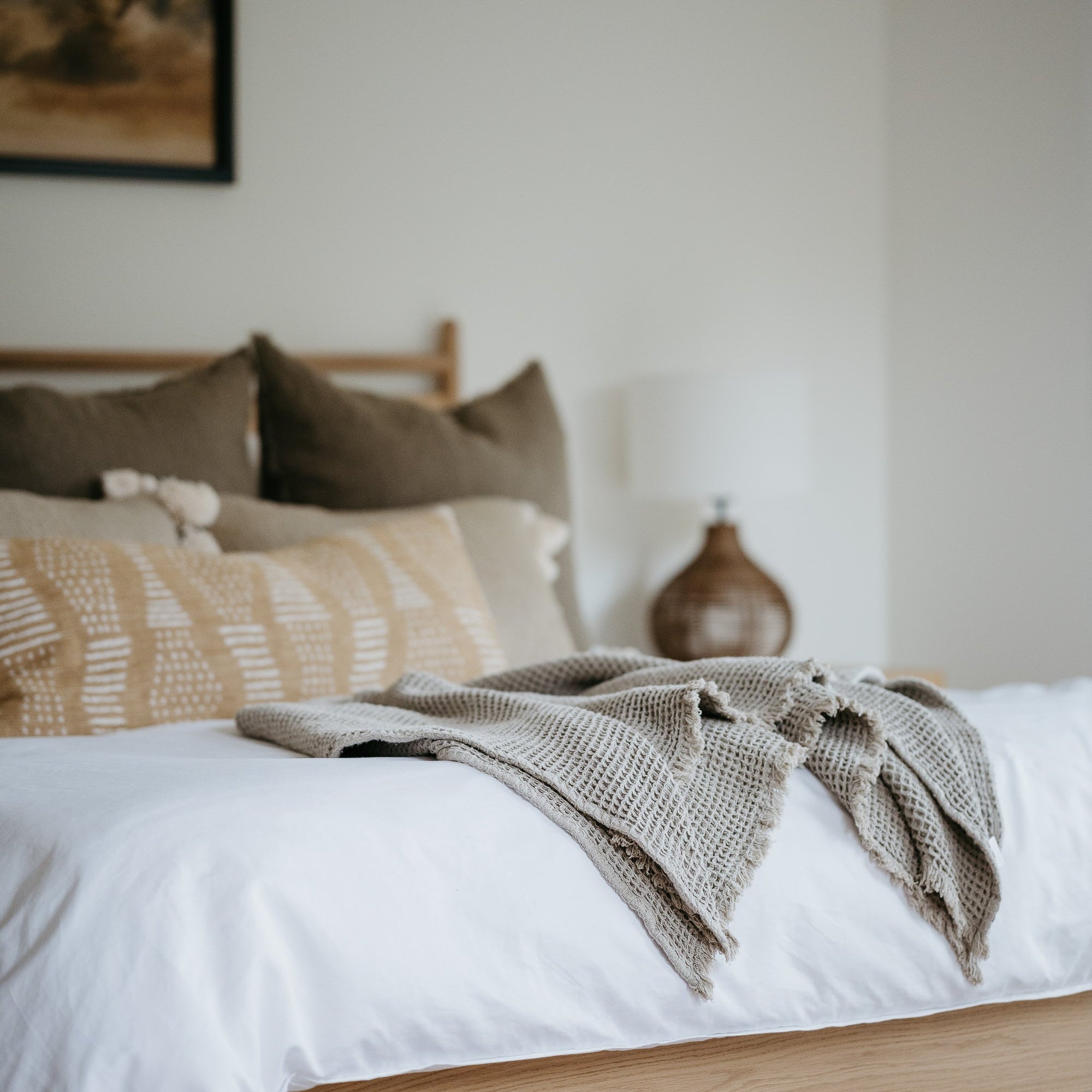 Neatly made bed with white linens and neutral pillows