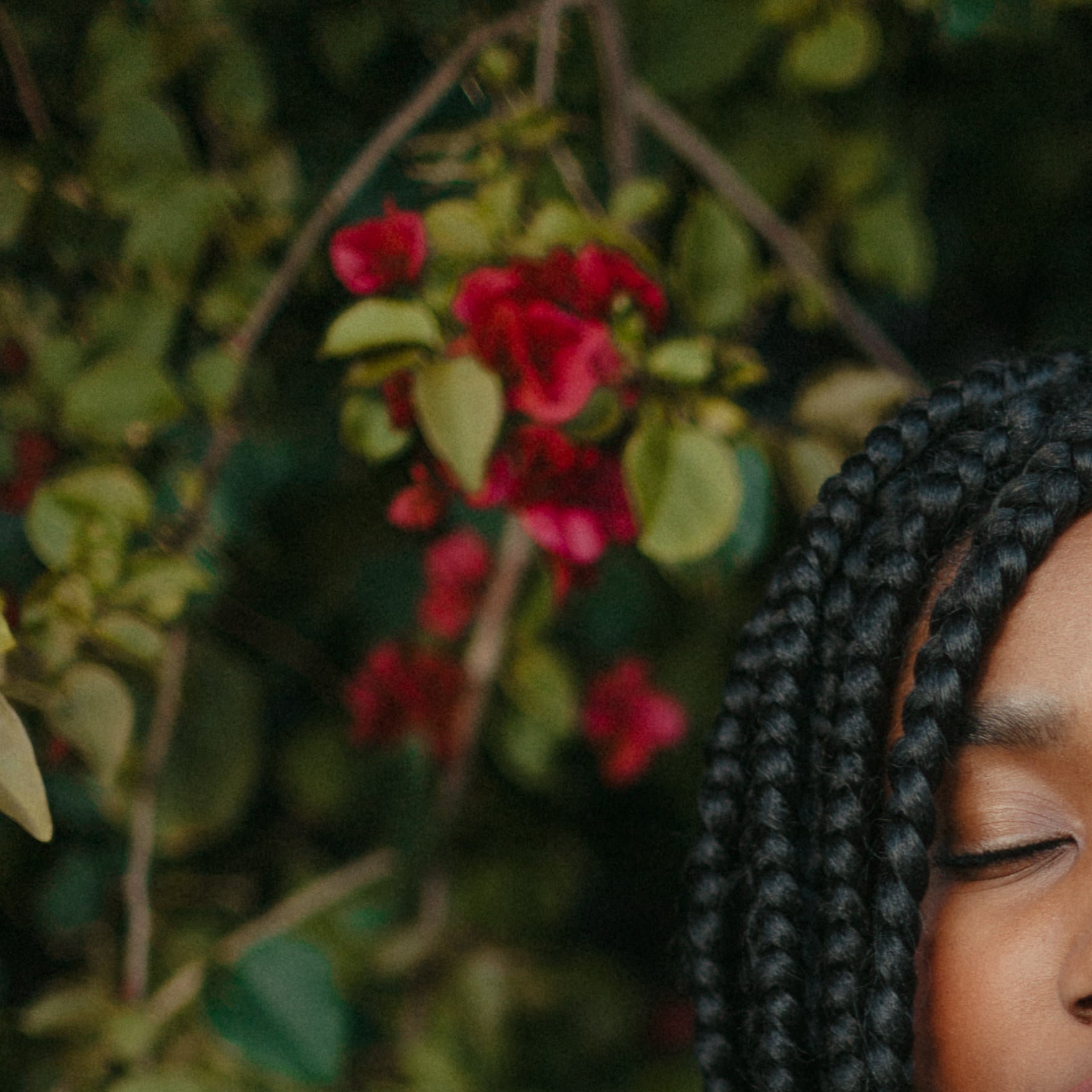 Woman with braids, eyes closed, beneath flowering branches