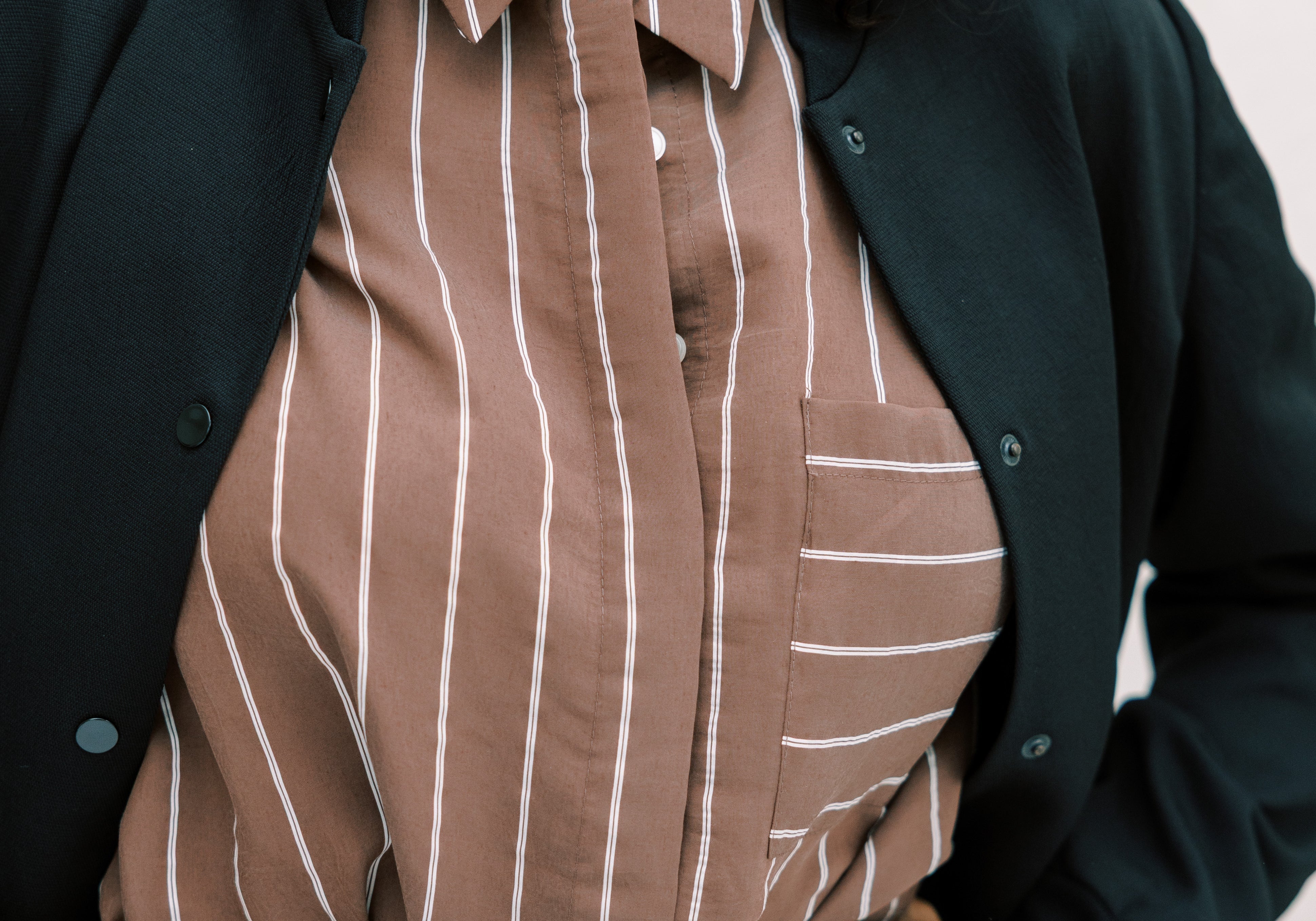 Woman in jeans and a striped shirt with hands resting on her stomach