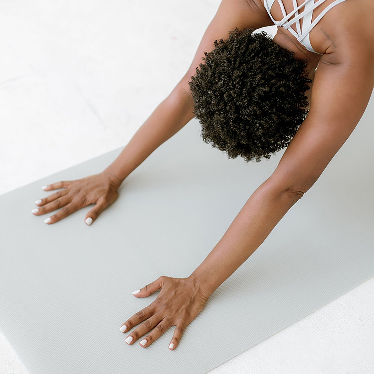 Overhead view of a woman folding forward on a yoga mat