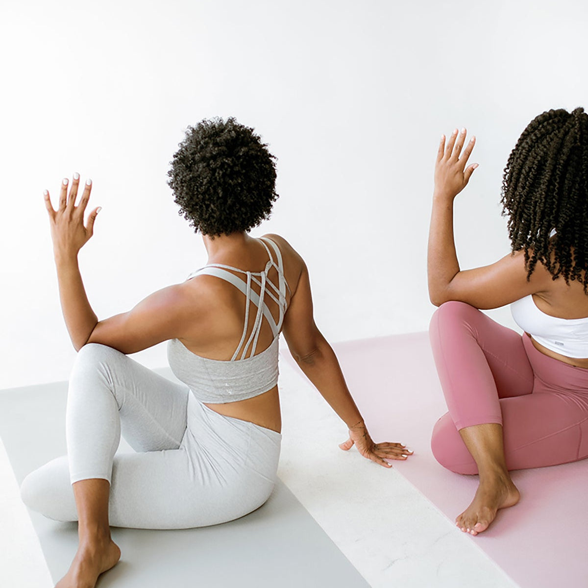 Two women doing seated twists on yoga mats