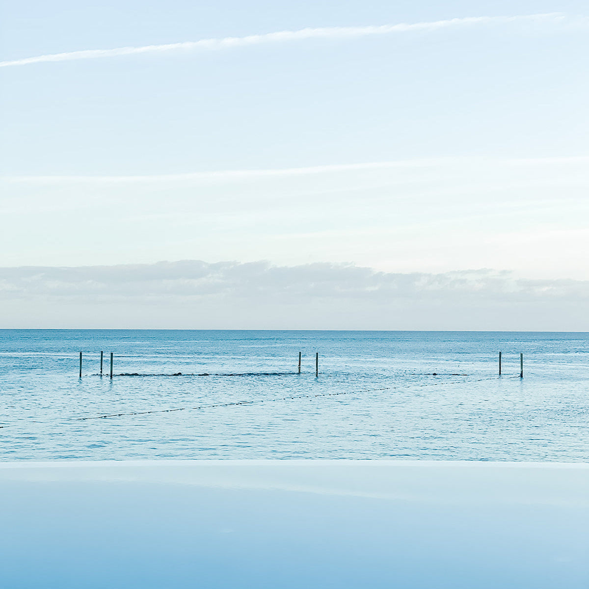Calm sea and blue sky seen from the edge of an ocean pool