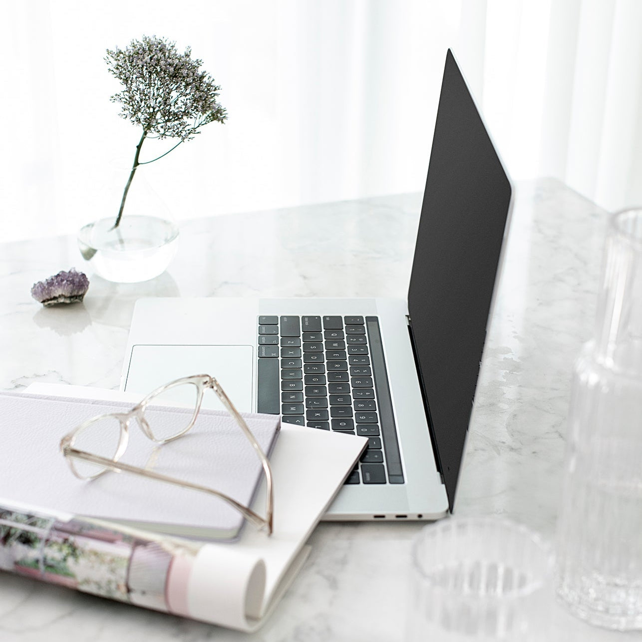 Laptop, glasses and a glass of water on a marble desk