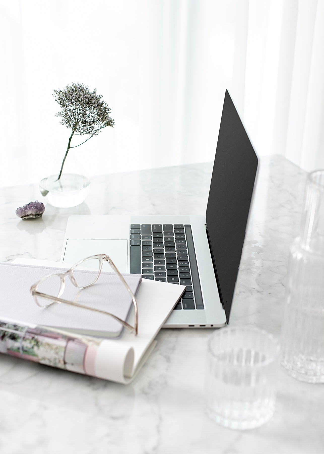 Laptop, glasses and a glass of water on a marble desk