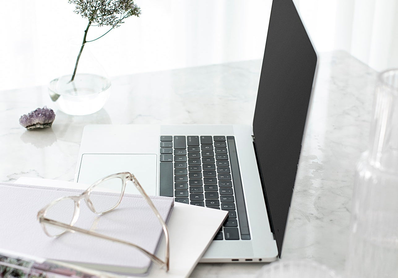 Laptop, glasses and a glass of water on a marble desk