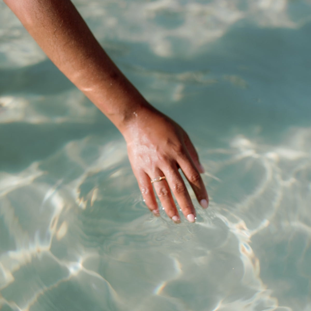 Hand trailing through clear, rippling water