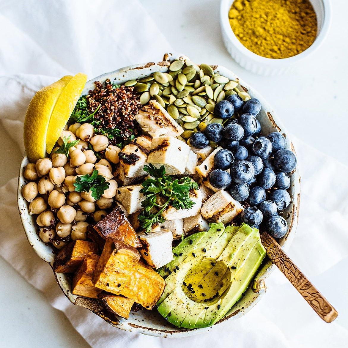 Fresh healthy food bowl with avocado, chickpeas, blueberries, greens, and lemon