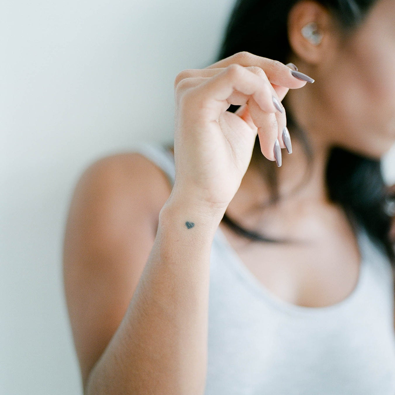Woman in a gray tank top touching her earring