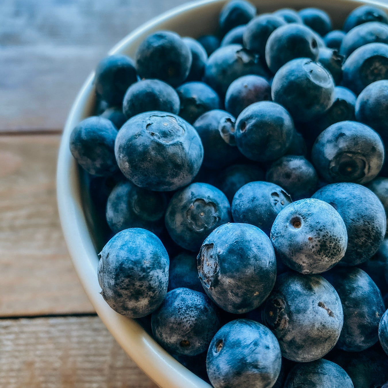 Bowl of fresh blueberries on a wooden table