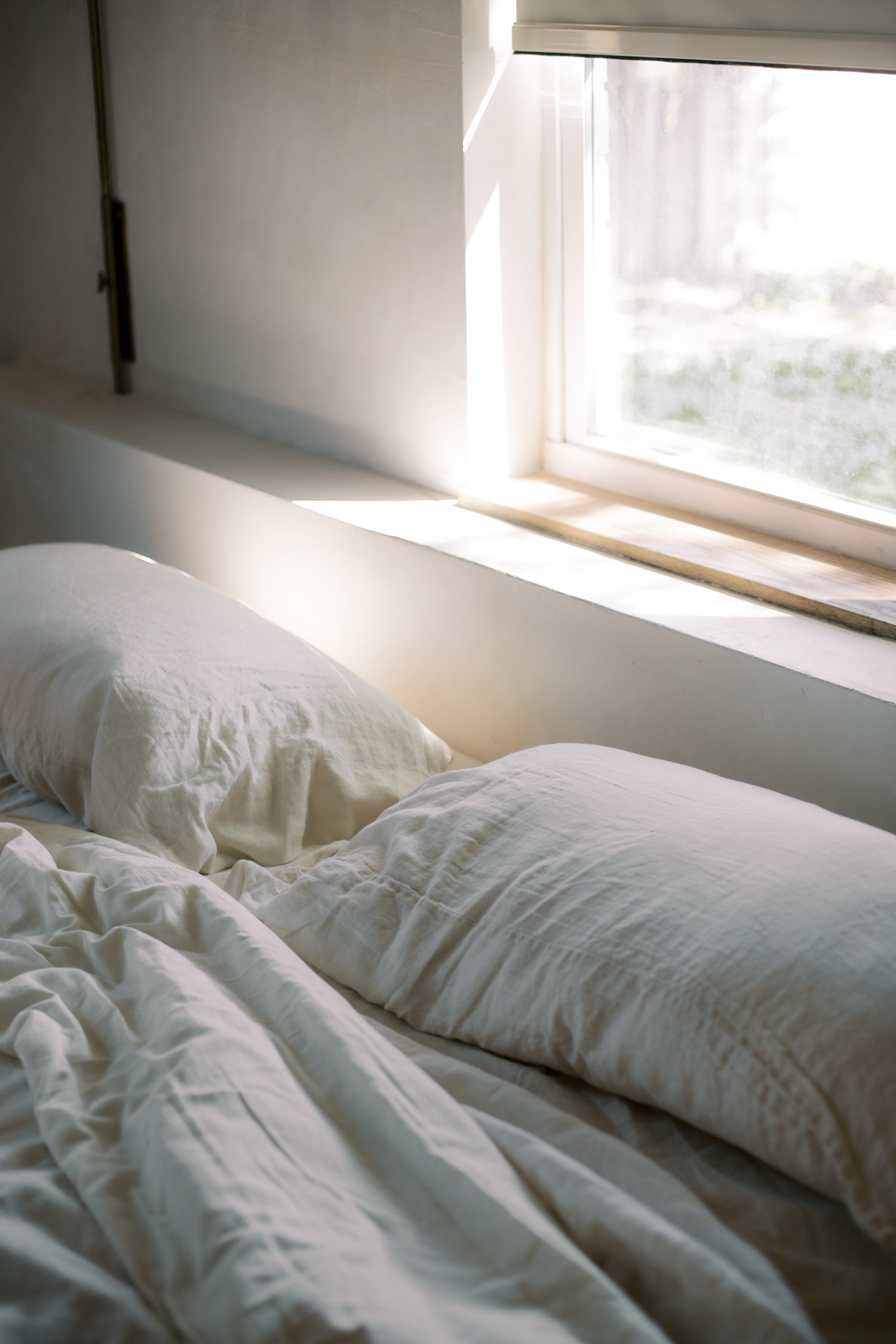 Cozy bed with morning sunlight streaming through a window, evoking restful sleep
