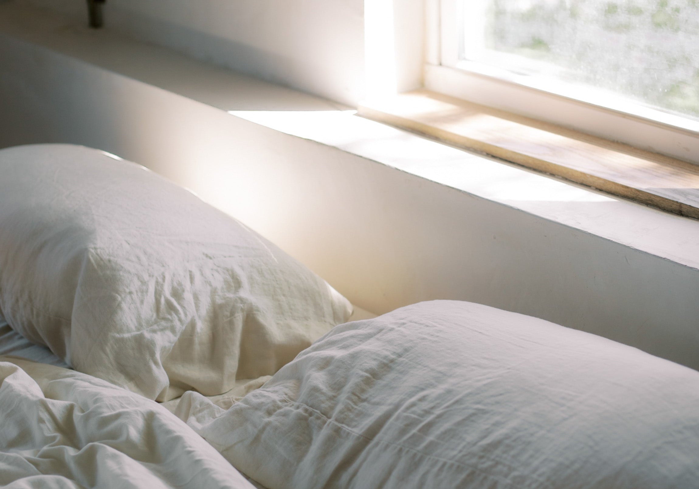 Cozy bed with morning sunlight streaming through a window, evoking restful sleep
