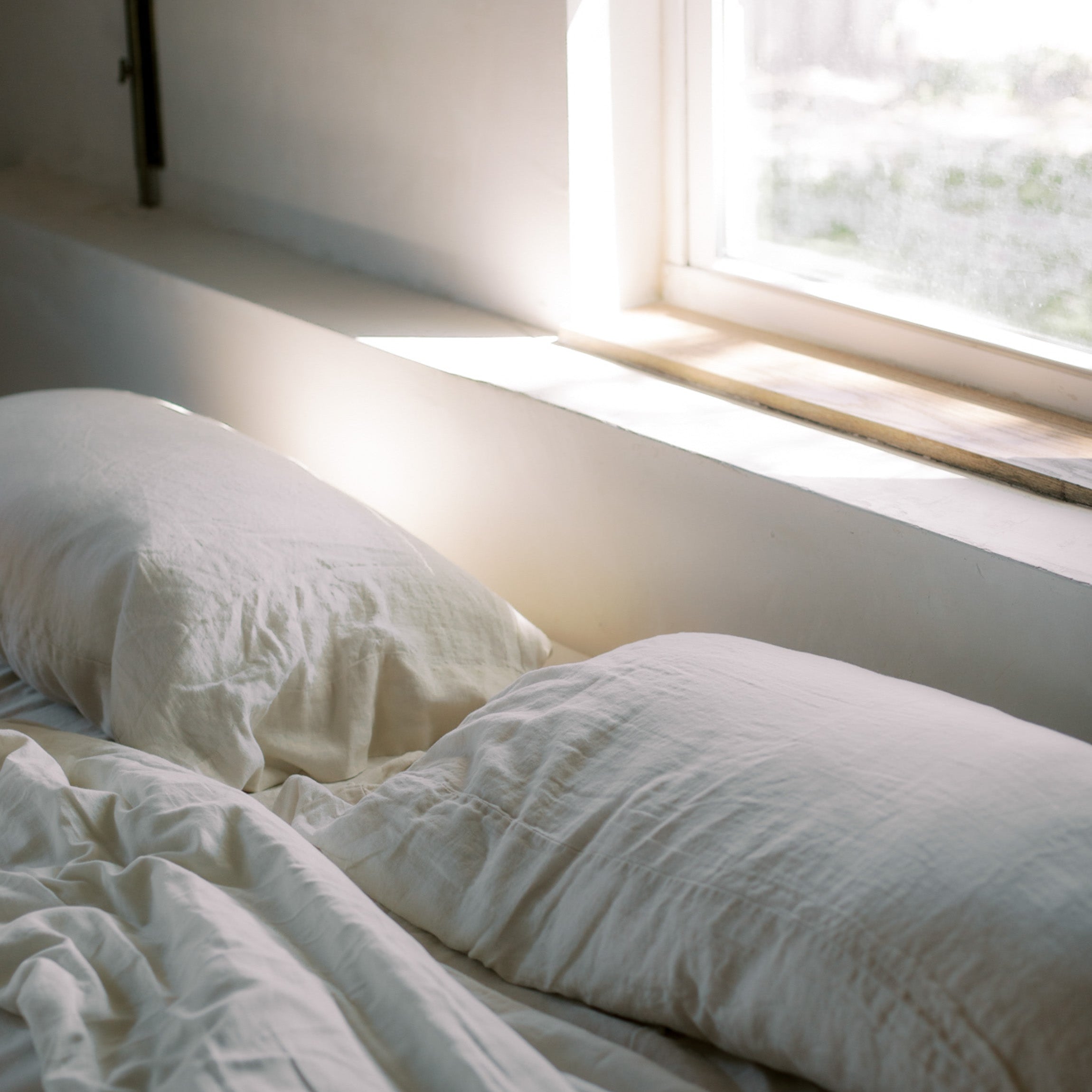 Cozy bed with morning sunlight streaming through a window, evoking restful sleep