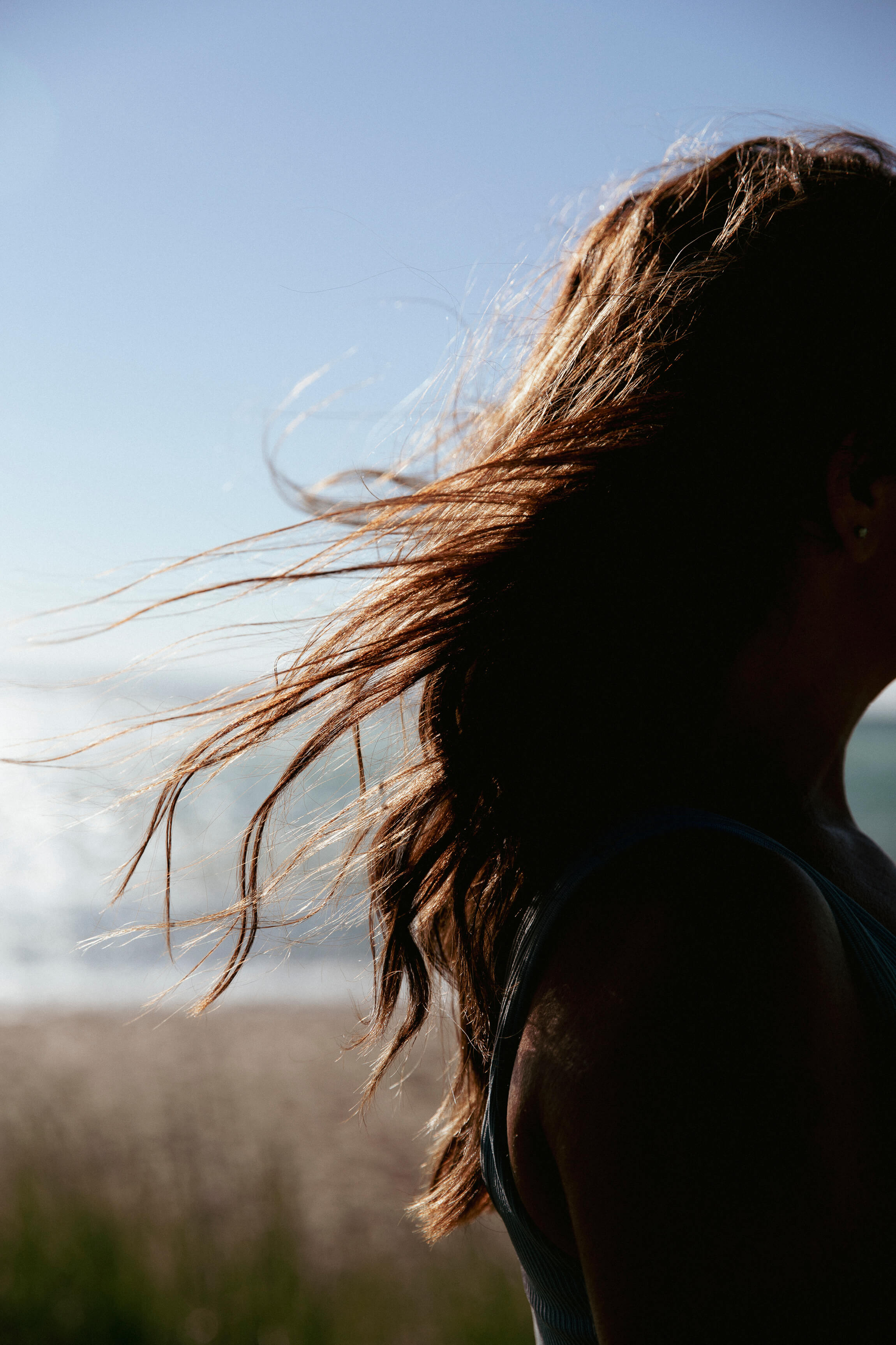 Woman with long, healthy hair blowing in the wind outdoors at golden hour