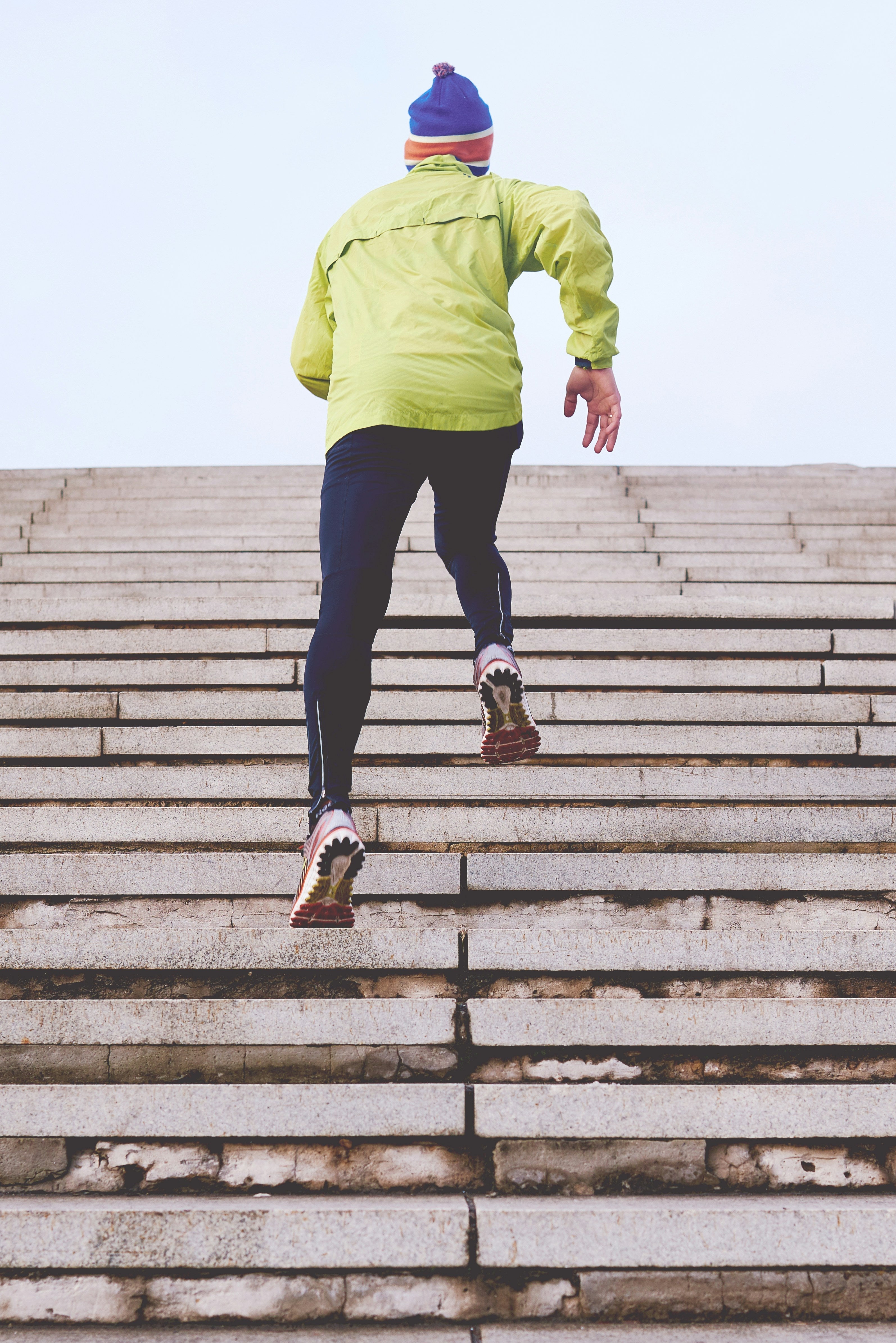 Runner in a bright green jacket climbing outdoor stone steps