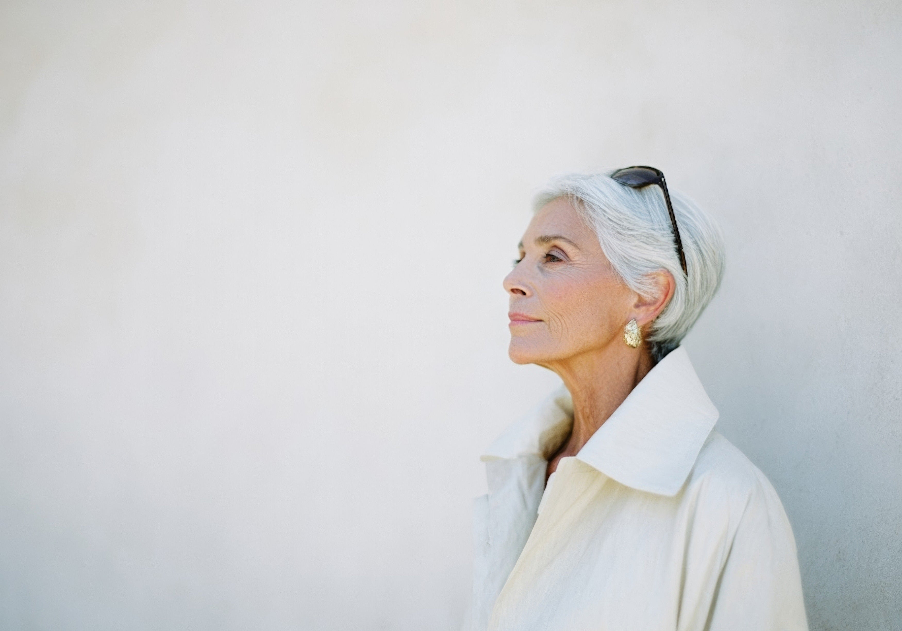 Elegant older woman with silver hair in a white coat, profile portrait