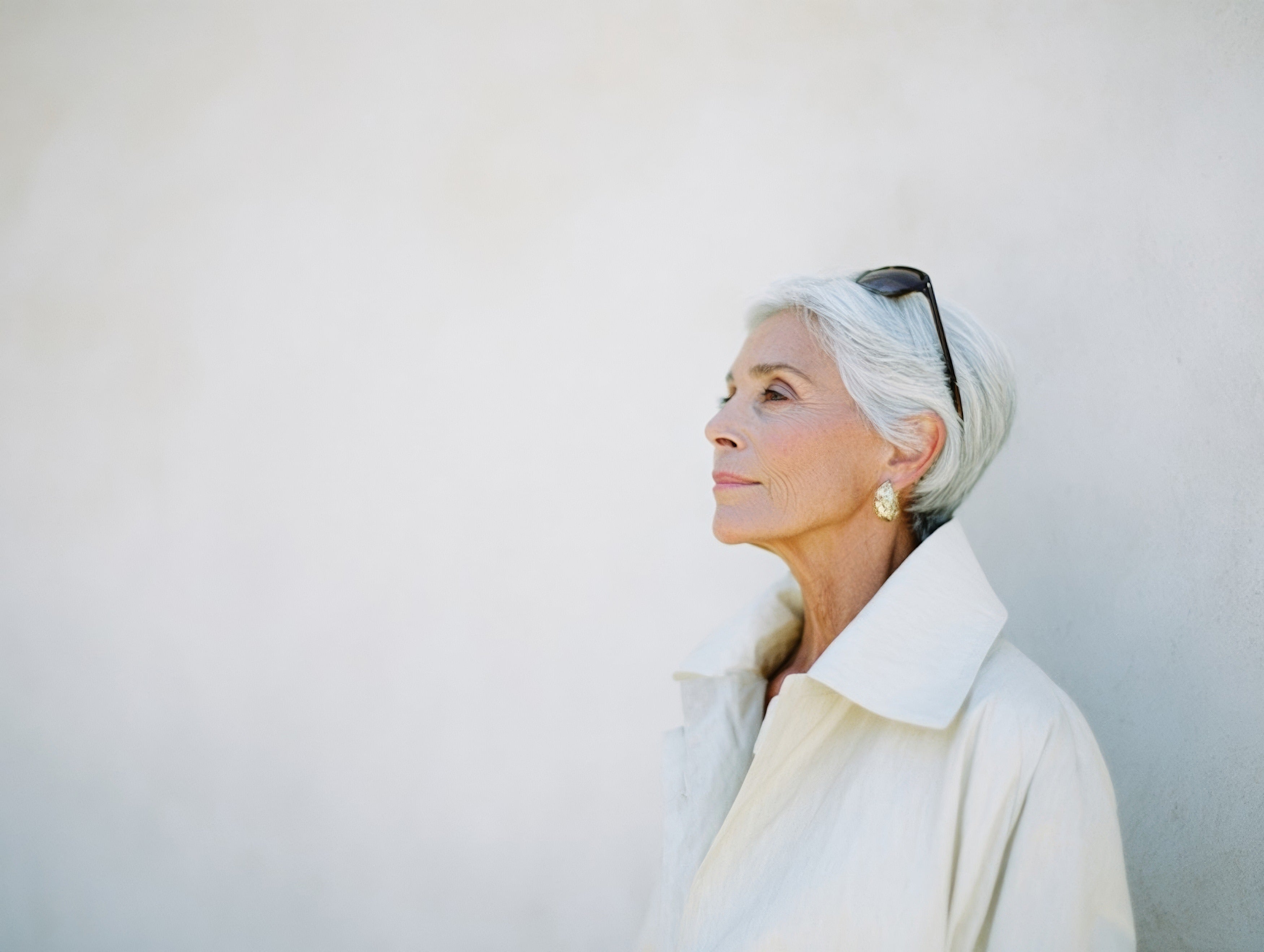 Elegant older woman with silver hair in a white coat, profile portrait