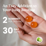 Hand holding two orange gummies with text about serving size and supply duration, on a neutral background.