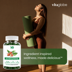 A woman in a brown outfit holds a rolled green mat in a sunlit room, with a bottle of VG Vita Globe Ashwagandha dietary supplement overlaid in the lower left and a green text banner reading 'Ingredient inspired wellness, made delicious.'.