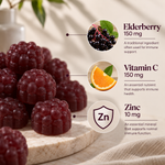 A styled product graphic showing a pile of dark red berry gummies on a marble slab, with ingredient callouts for elderberry, vitamin C, and zinc on a light beige background.