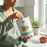 Woman holding a supplement package labeled 'VG Ashwagandha' in a bright kitchen.