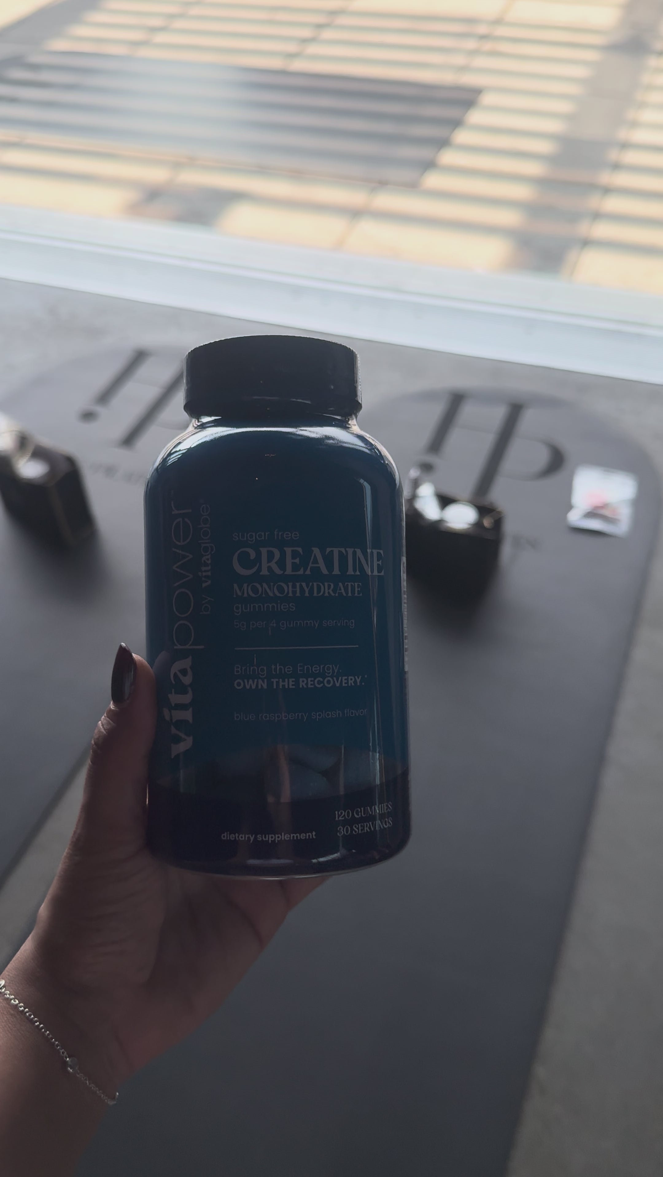 Hand holding a bottle of VitaPower Sugar-Free Creatine Monohydrate Gummies at a Pilates studio