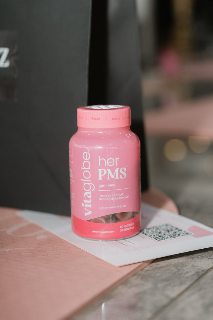 Vita Globe Her PMS gummies bottle, lush strawberry flavor, at a Pilates event